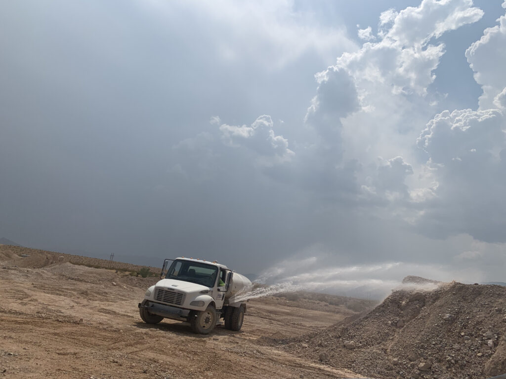 A truck spraying water on a muddy ground